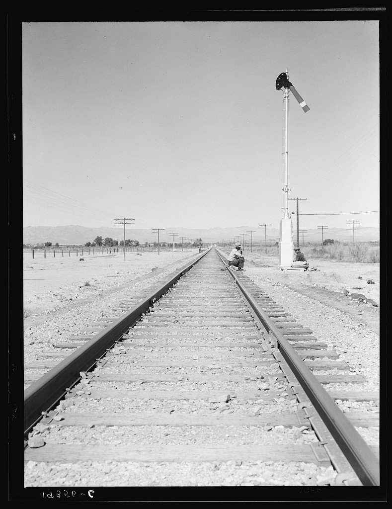 Looking east down the railroad track, near Calipatria, California. Single men, itinerants with "bindles" waiting for the
